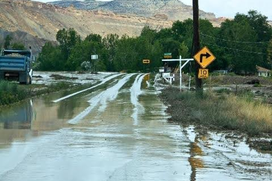 A flooded road with trees and mountains in the background.