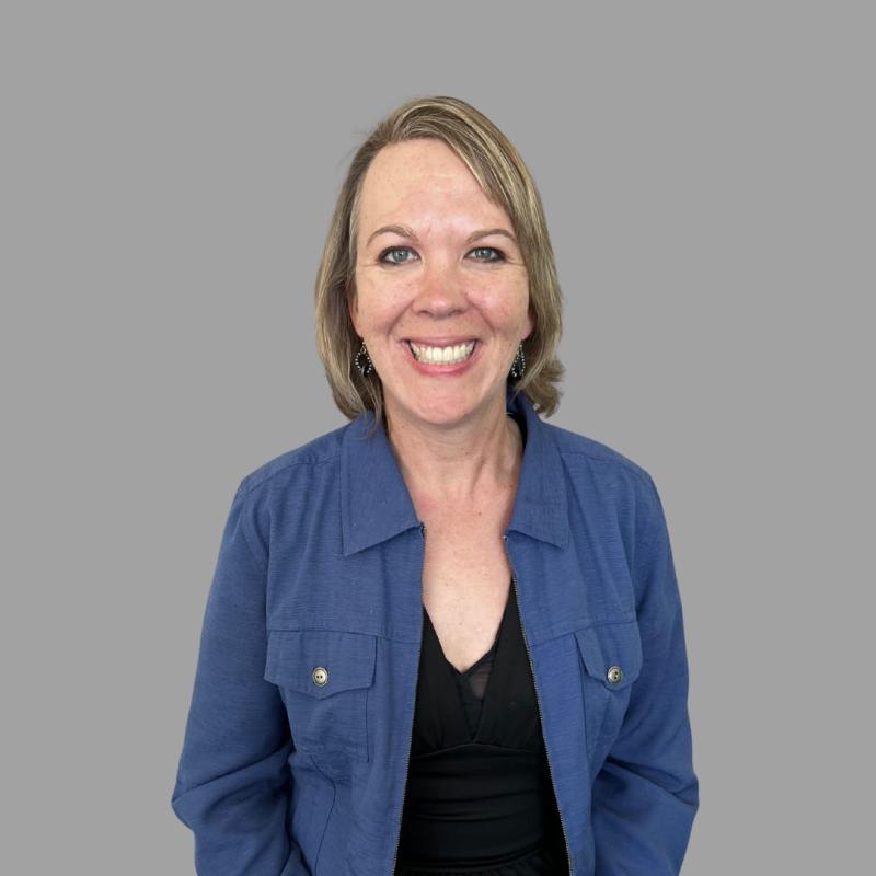 Photograph of a smiling, professionally dressed woman in blue suit jacket.